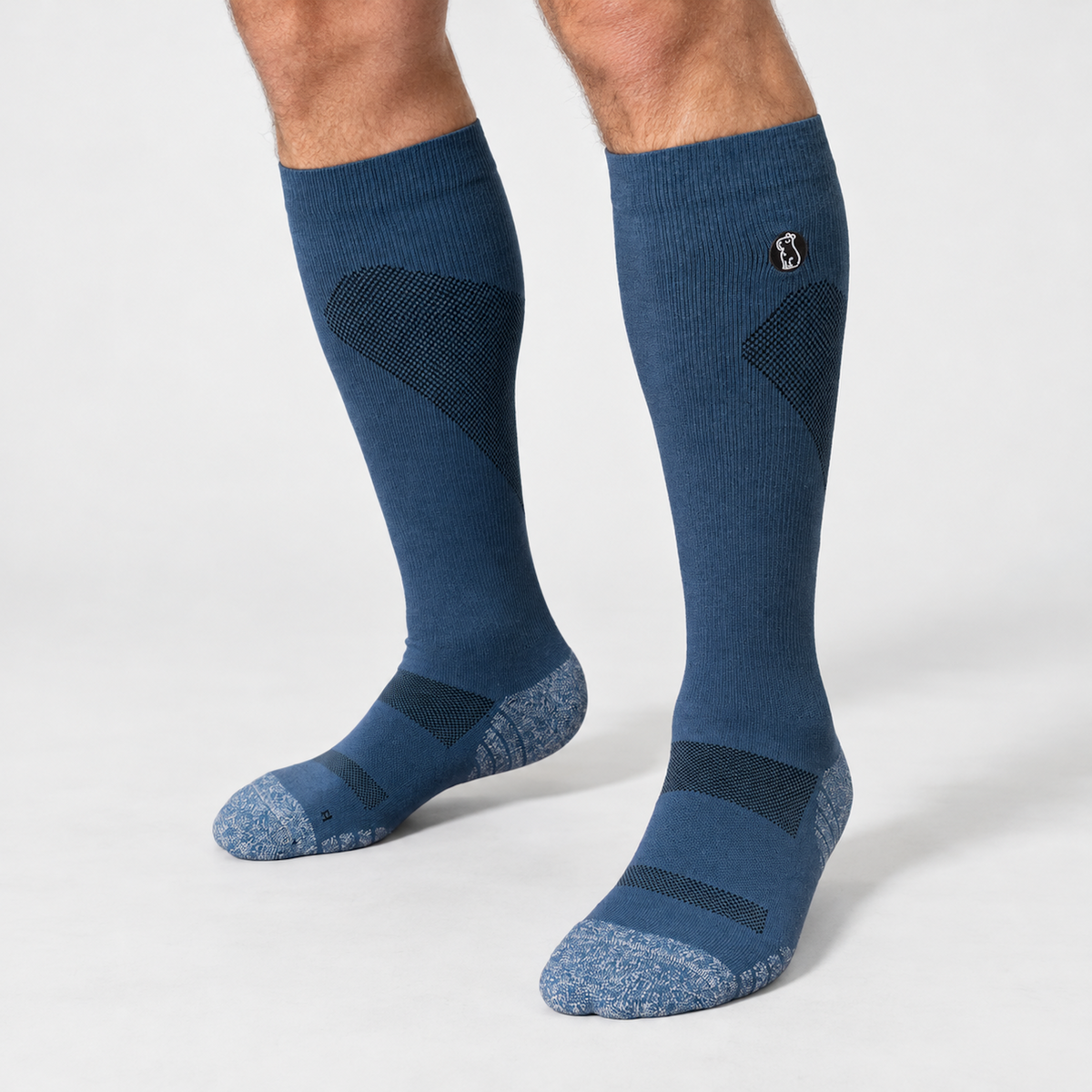Male model wearing navy blue compression sock with light blue toe and heel on light grey background