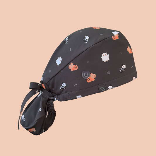 Side view of black ponytail scrub cap featuring capybaras wearing pumpkin, ghost, and skeleton costumes