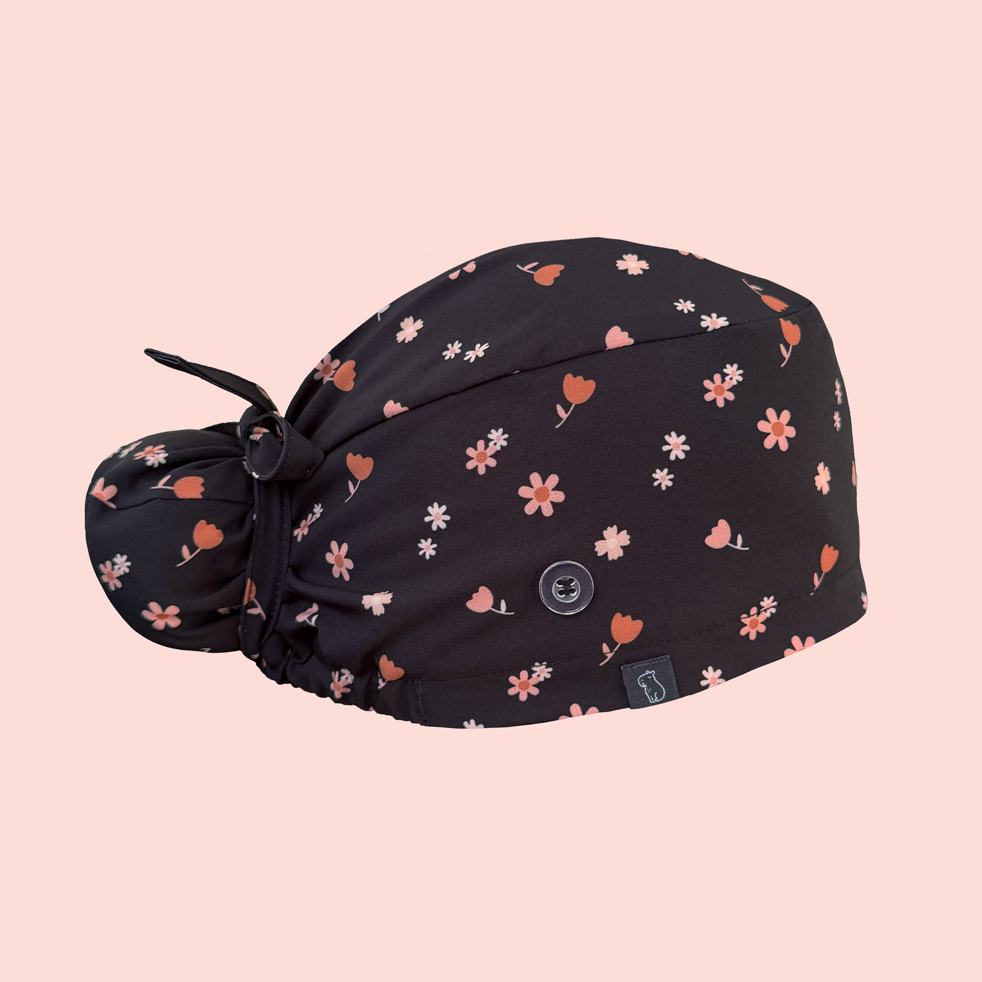 Side view of bun scrub cap featuring pink/peach flowers on a charcoal background