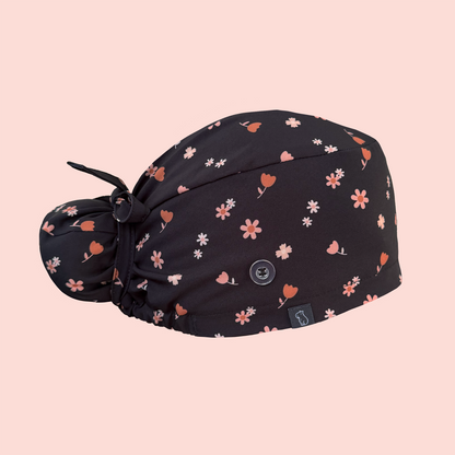 Side view of bun scrub cap featuring pink/peach flowers on a charcoal background