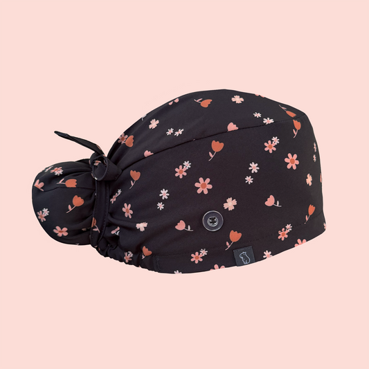 Side view of bun scrub cap featuring pink/peach flowers on a charcoal background