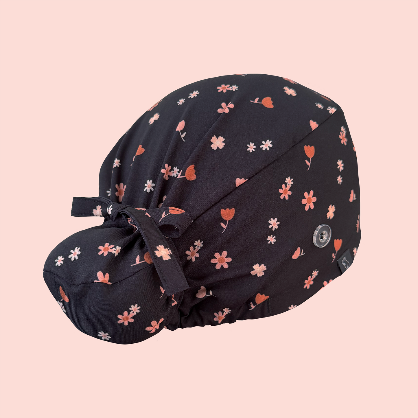 Rear view of bun scrub cap featuring pink/peach flowers on a charcoal background