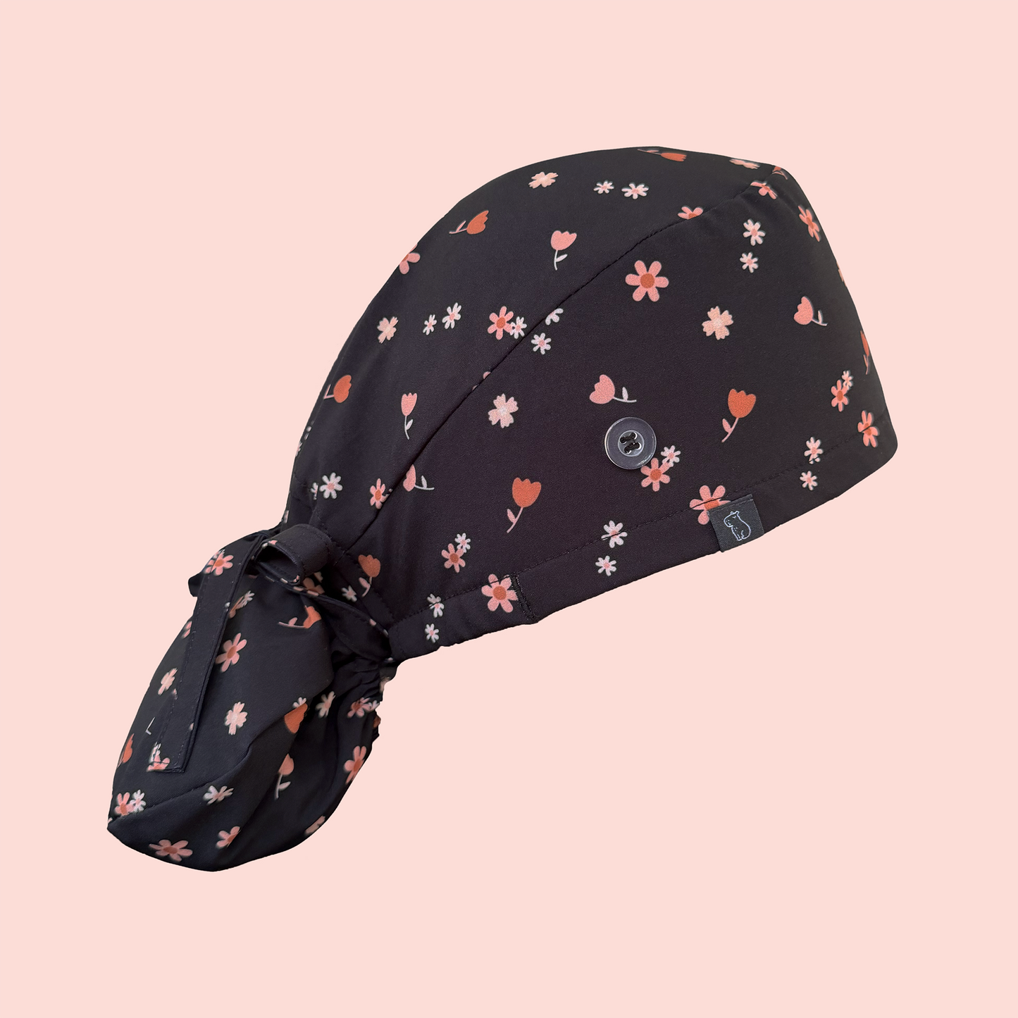 Side view of ponytail scrub cap featuring pink/peach flowers on a charcoal background