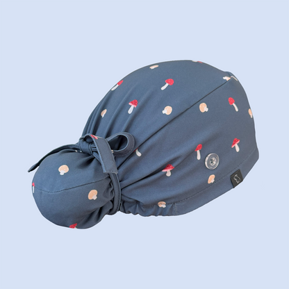 Rear view of blue Bun scrub cap decorated with a whimsical mushroom print in red, yellow, and white