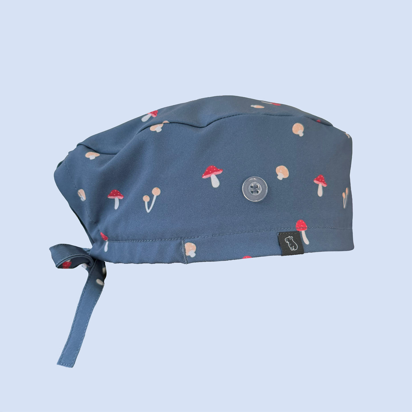 Side view of blue classic scrub cap decorated with a whimsical mushroom print in red, yellow, and white