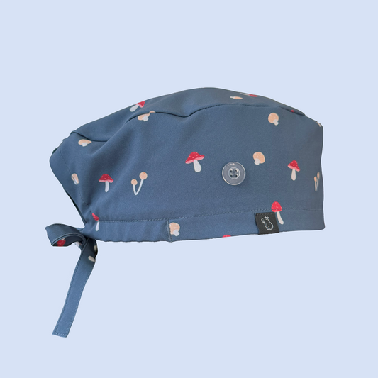 Side view of blue classic scrub cap decorated with a whimsical mushroom print in red, yellow, and white